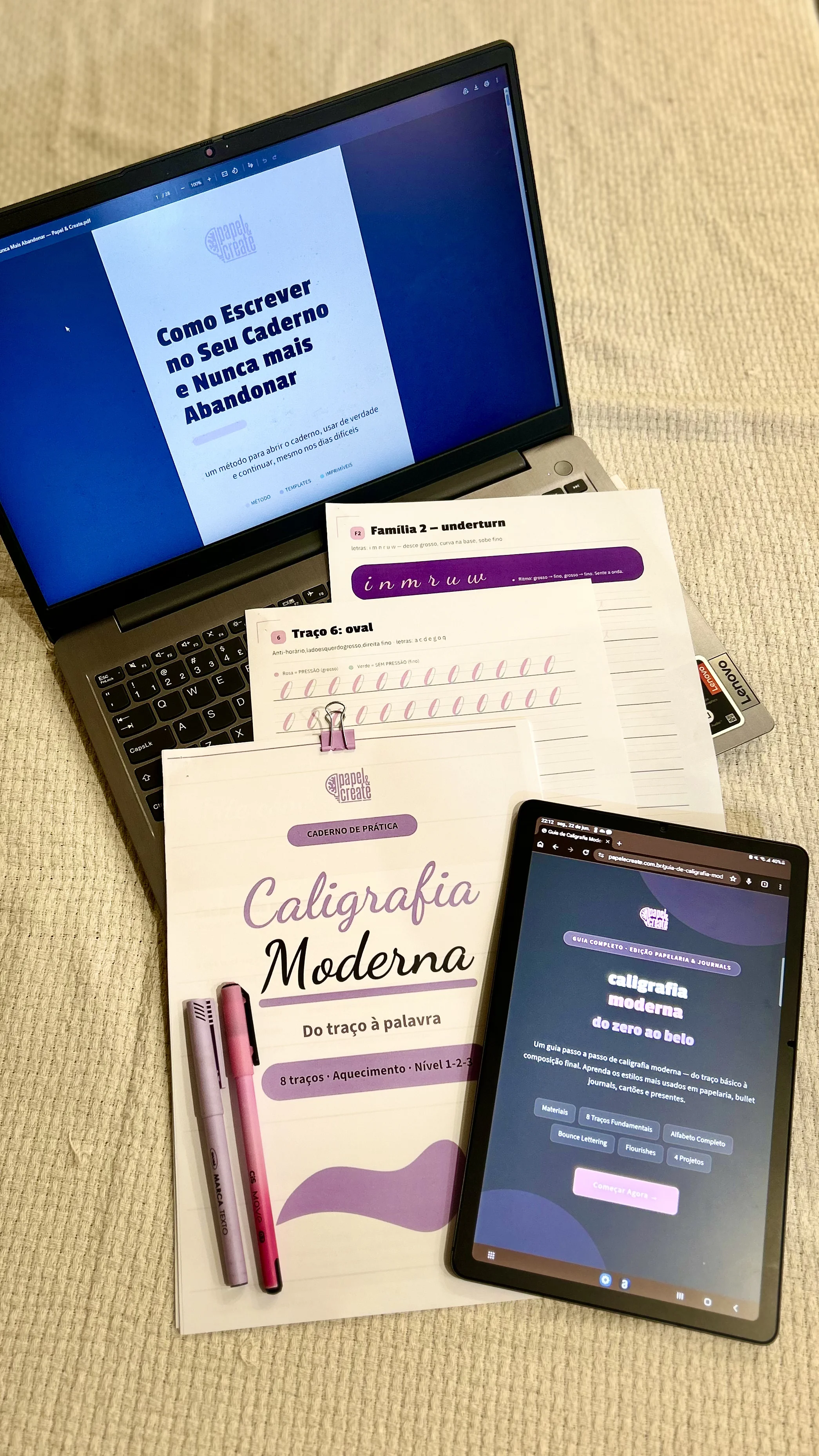 Flat lay dos três produtos: e-book, caderno de prática e ferramenta web sobre mesa creme